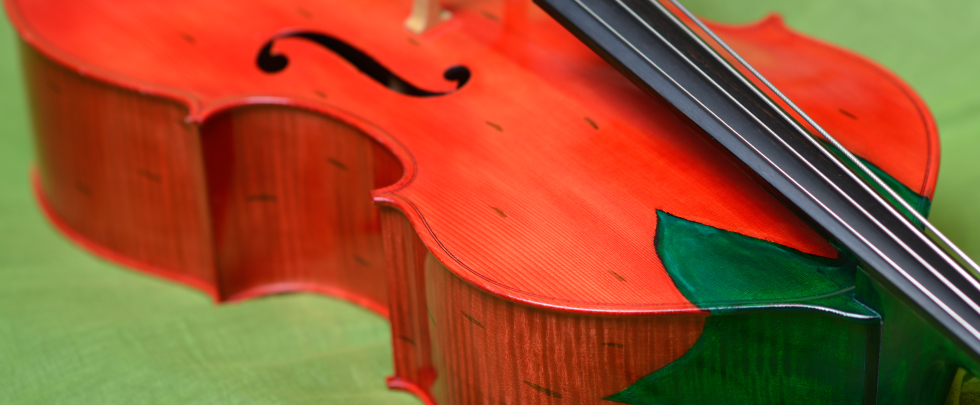 Ein roter Kinderkontrabass mit schwarzen Punkten und grünen Blättern am Halseinsatz: Modell Erdbeere