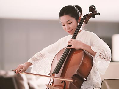 Eine junge, elegant gekleidete Frau spielt Cello.